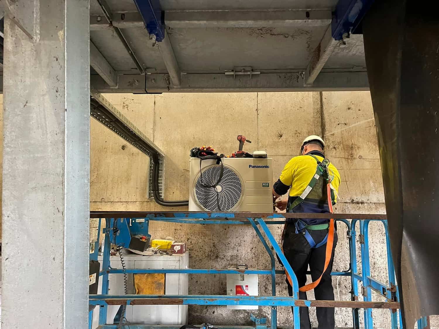 Worker in Safety Harness on Lift Installing Unit — Leader Air Conditioning in Queanbeyan, NSW
