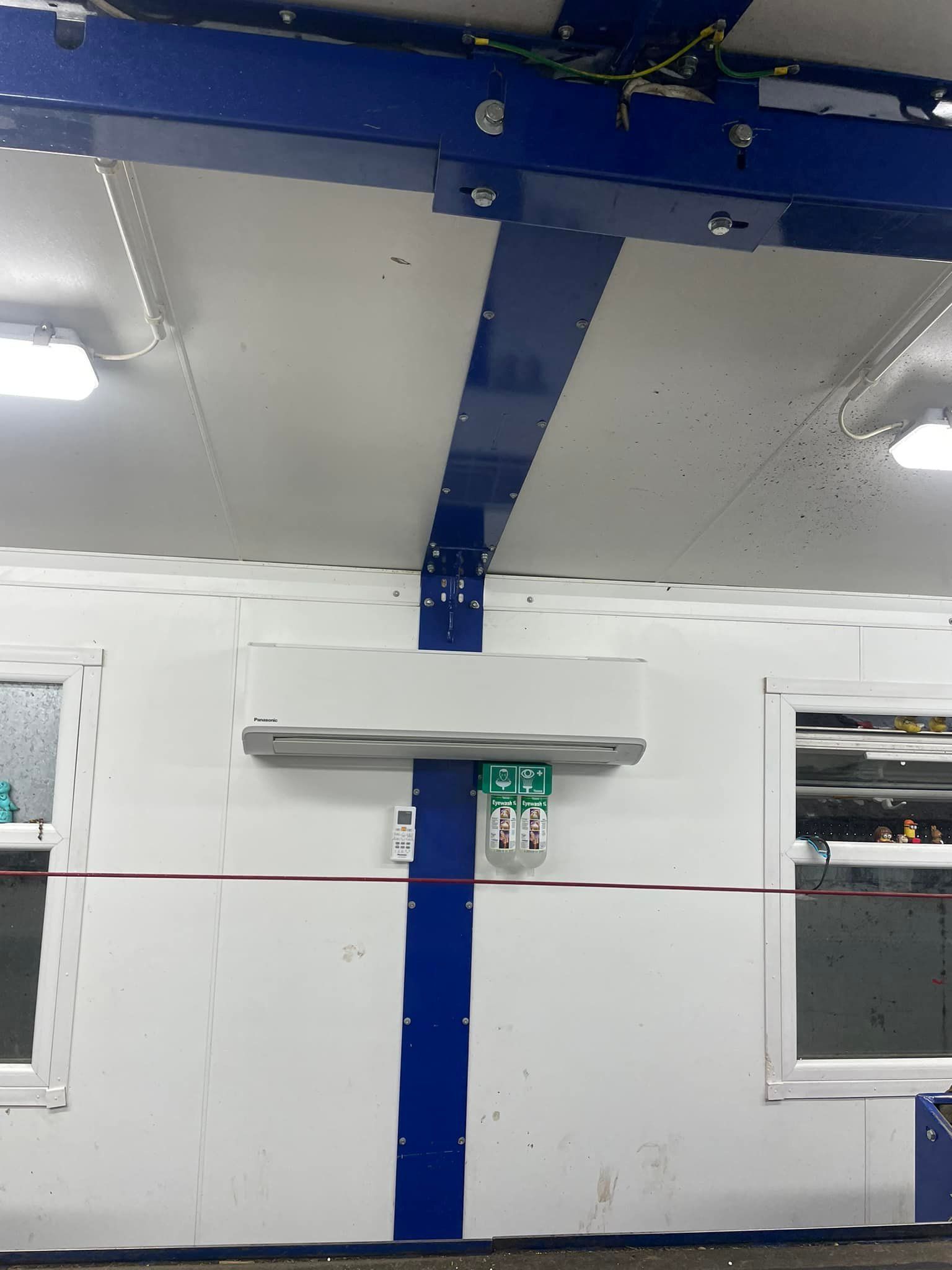 White-walled room with blue accents and metal beam. A panel with buttons and windows. Red tape across the center. — Leader Air Conditioning in Wagga Wagga, NSW