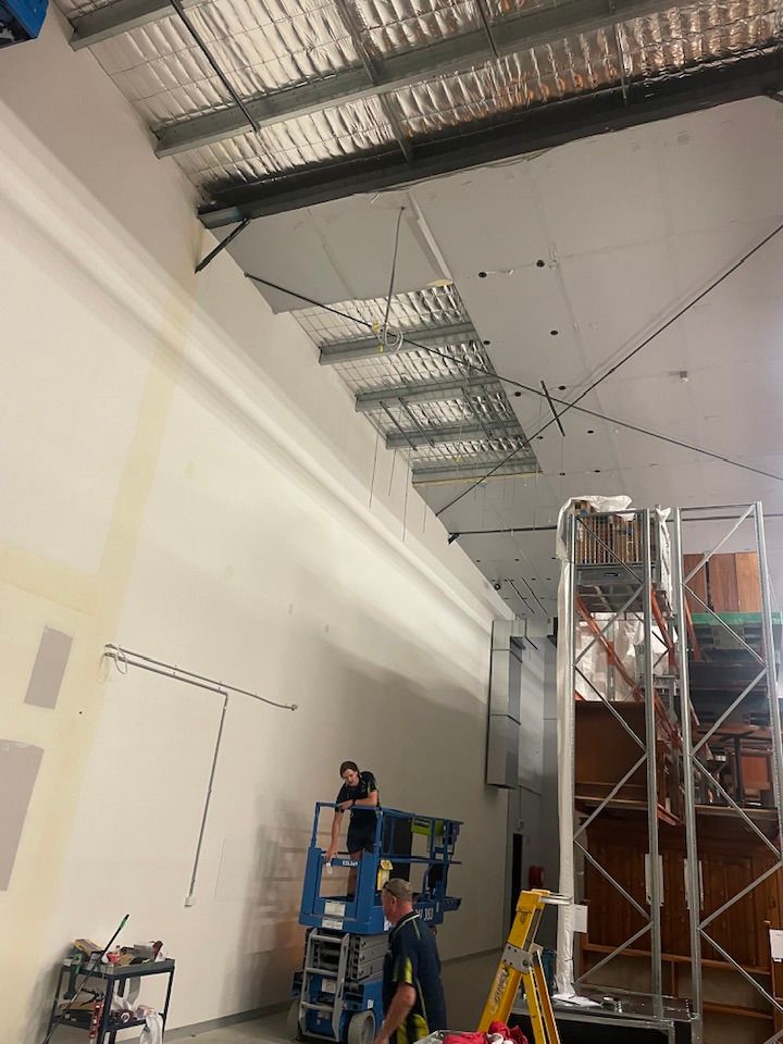 People Working in A Warehouse Installing Ceiling Panels and Electrical Wiring — Leader Air Conditioning in Queanbeyan, NSW