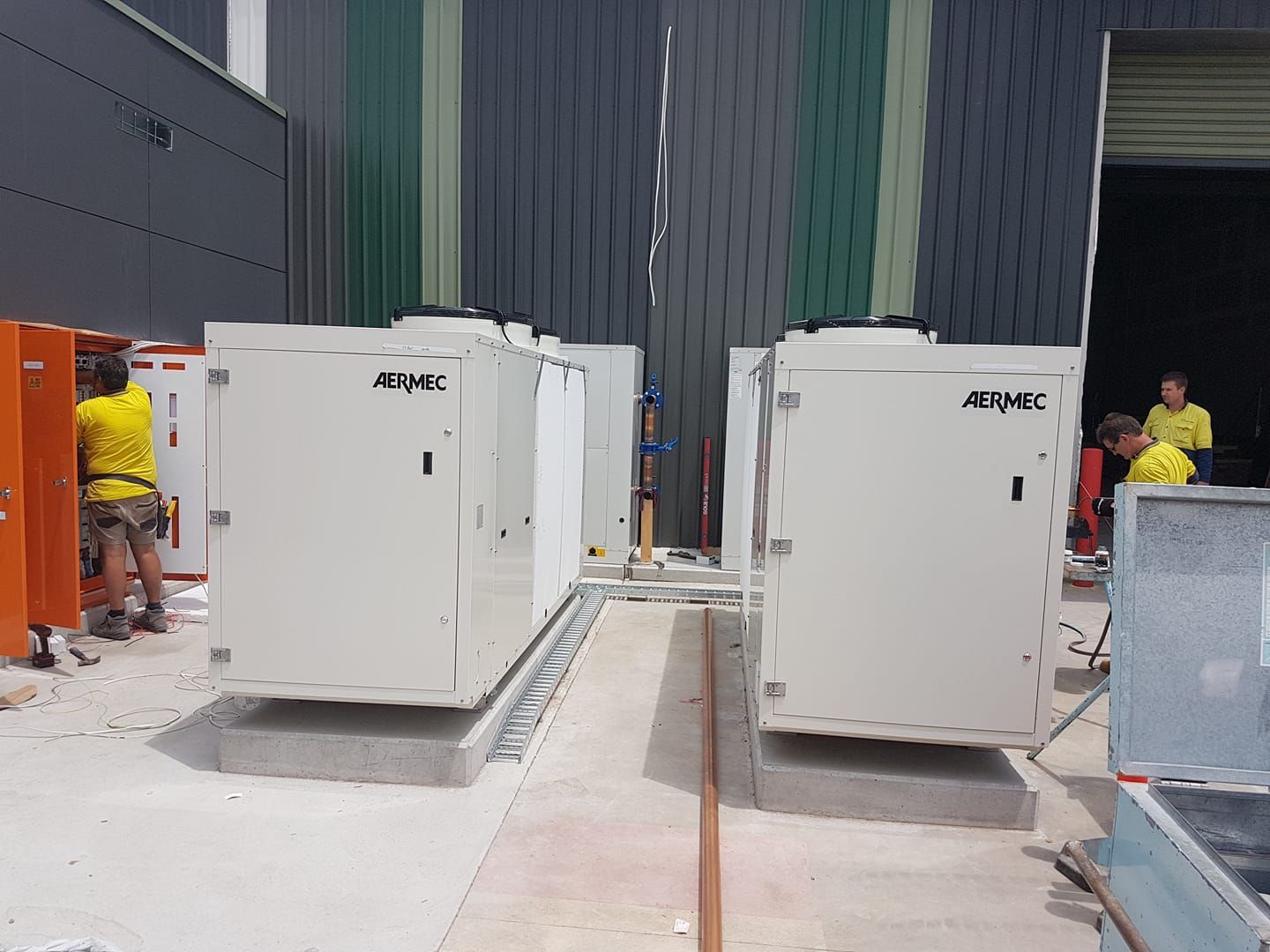 Workers Installing HVAC Units in Front of A Building — Leader Air Conditioning in Queanbeyan, NSW