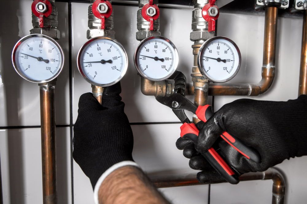 A Person Wearing Black Gloves Using Pliers on Plumbing — Leader Air Conditioning in Queanbeyan, NSW