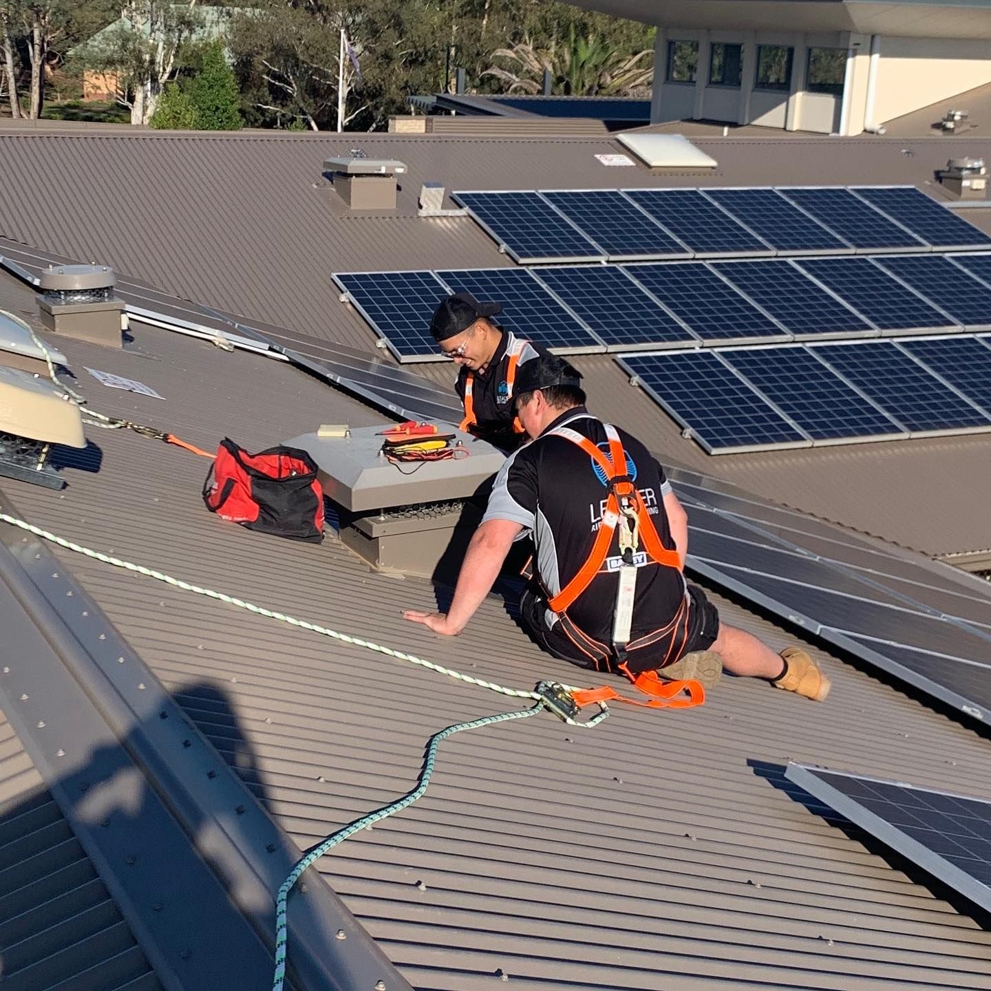 Two Workers on A Metal Roof with Solar Panels — Leader Air Conditioning in Queanbeyan, NSW