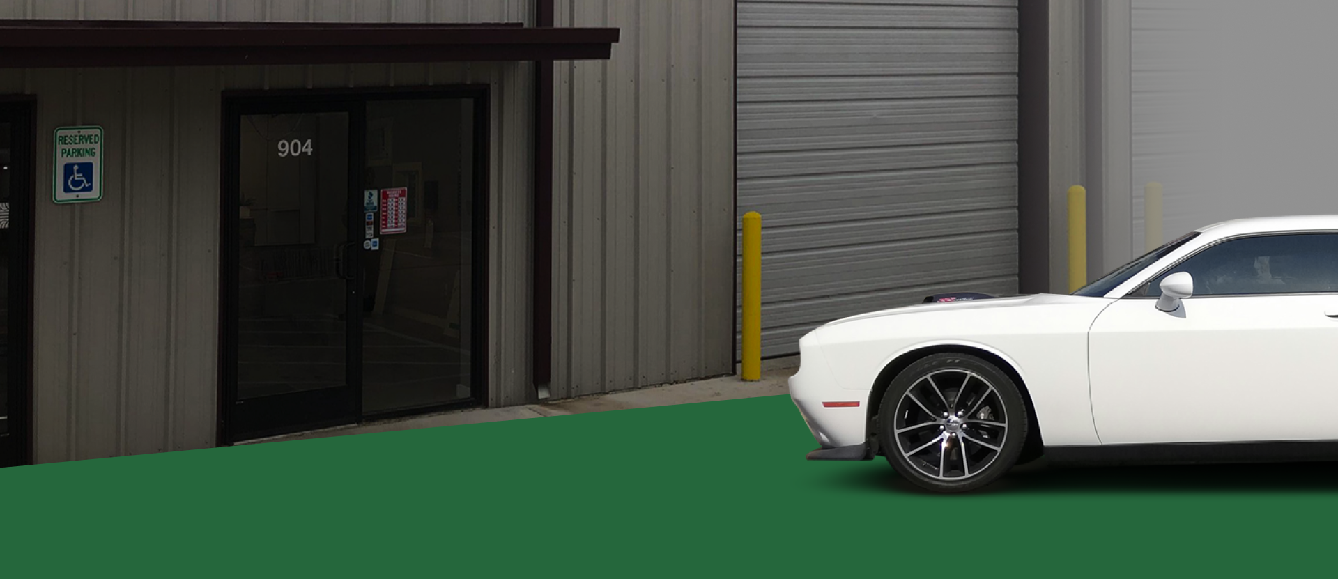 White car parked in front of a building with a green lawn. The building has a closed garage door and entrance. | Jeremi's Auto Repair
