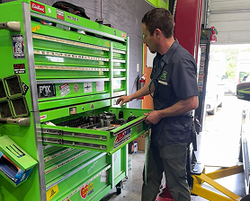 Mechanic opening a drawer in a bright green tool chest in a garage. | Jeremi's Auto Repair