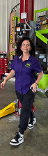 Woman in purple shirt and black pants walks in auto shop. Wearing black and white sneakers. | Jeremi's Auto Repair