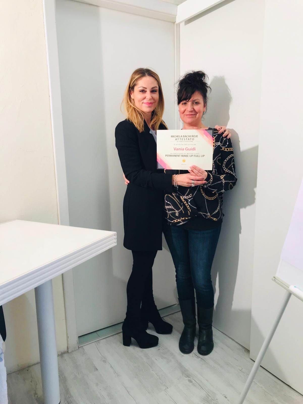 Due donne sono in piedi una accanto all'altra e tengono in mano un certificato.