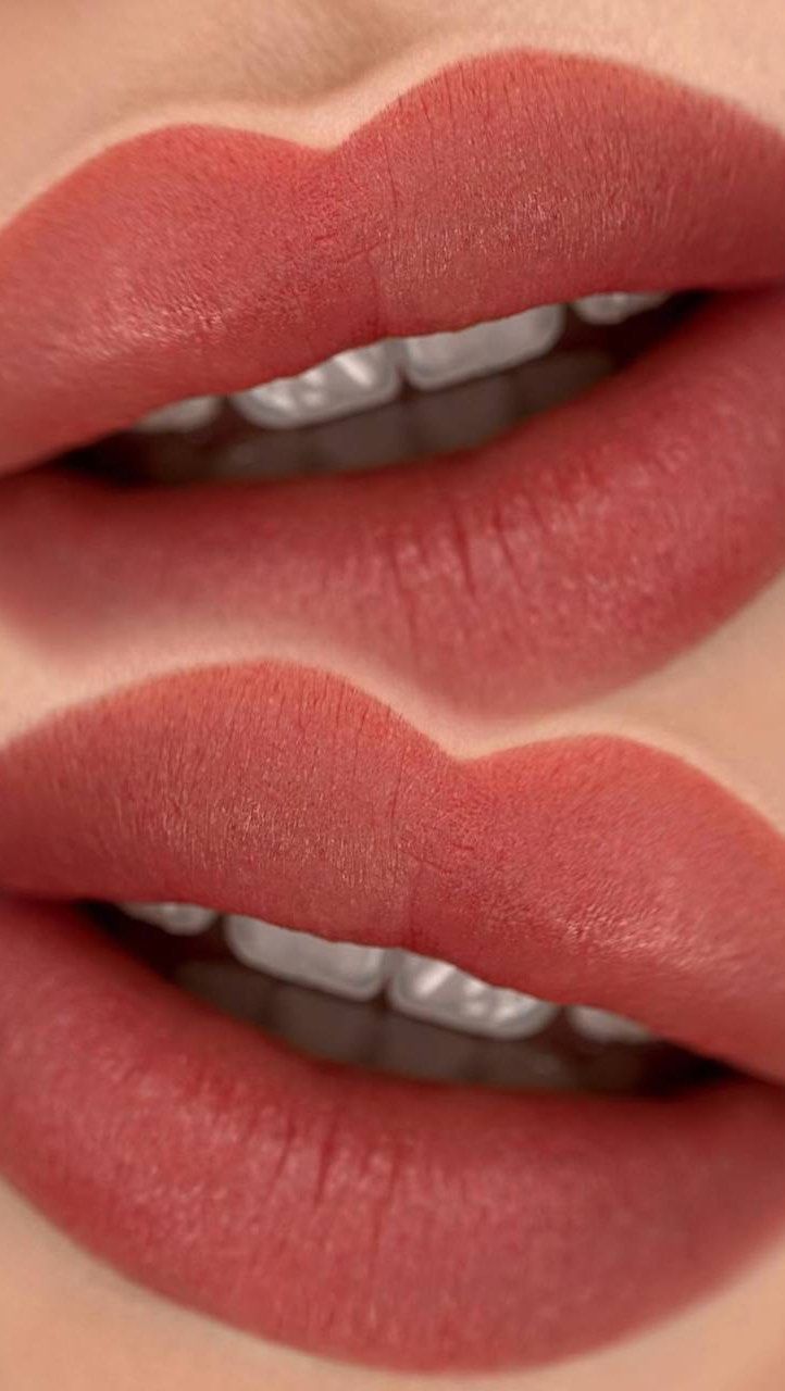Un primo piano delle labbra di una donna con rossetto rosso e denti bianchi.