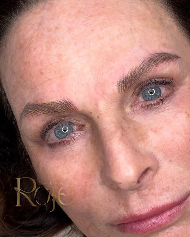 Un primo piano del viso di una donna con occhi azzurri e lentiggini.