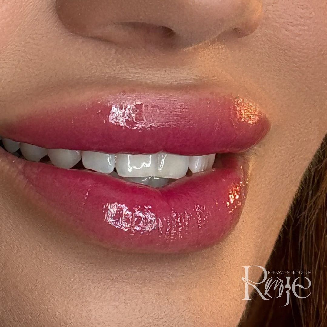 Un primo piano delle labbra di una donna con rossetto rosa e denti bianchi.