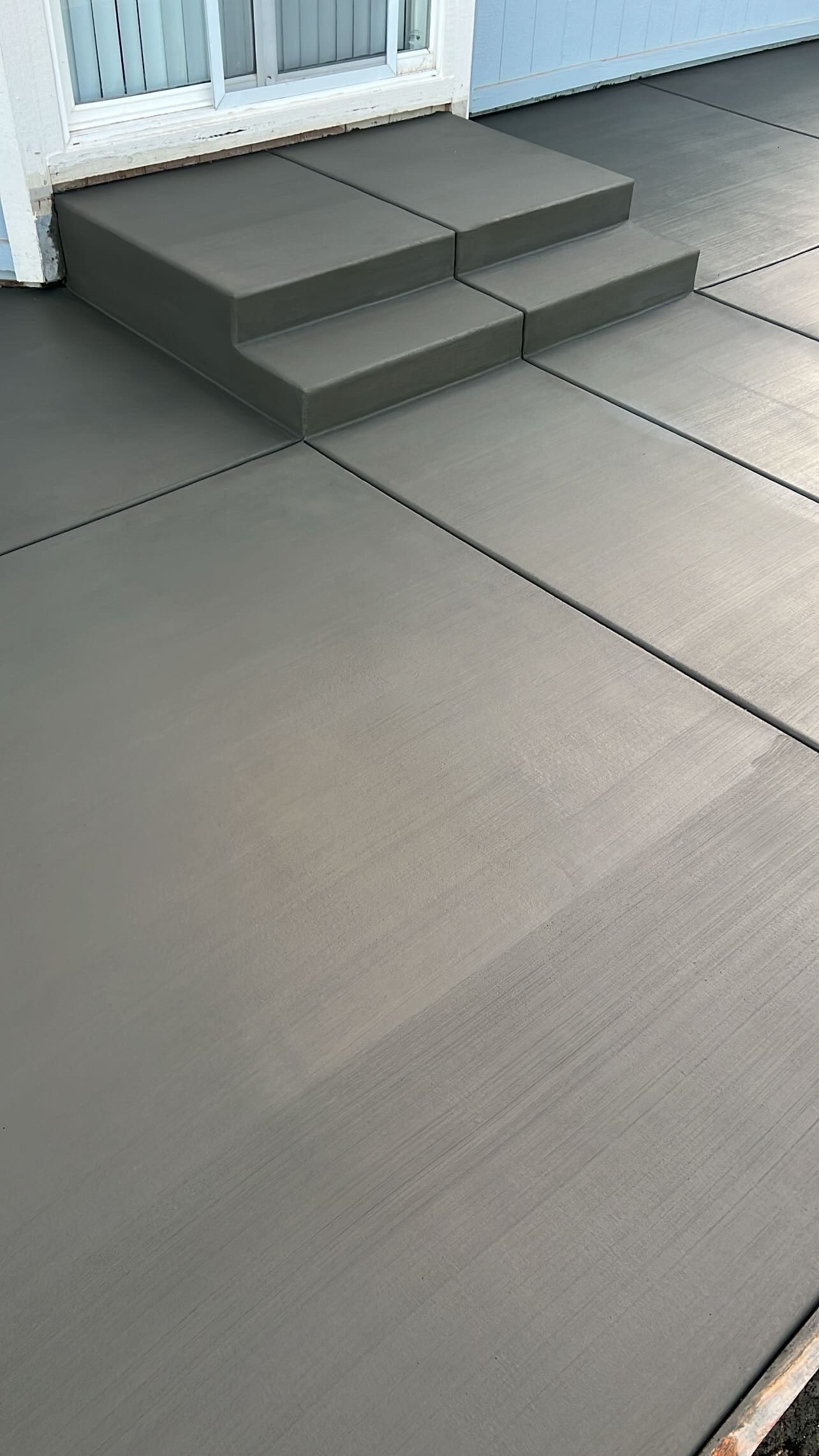 A concrete driveway with steps leading up to a house.