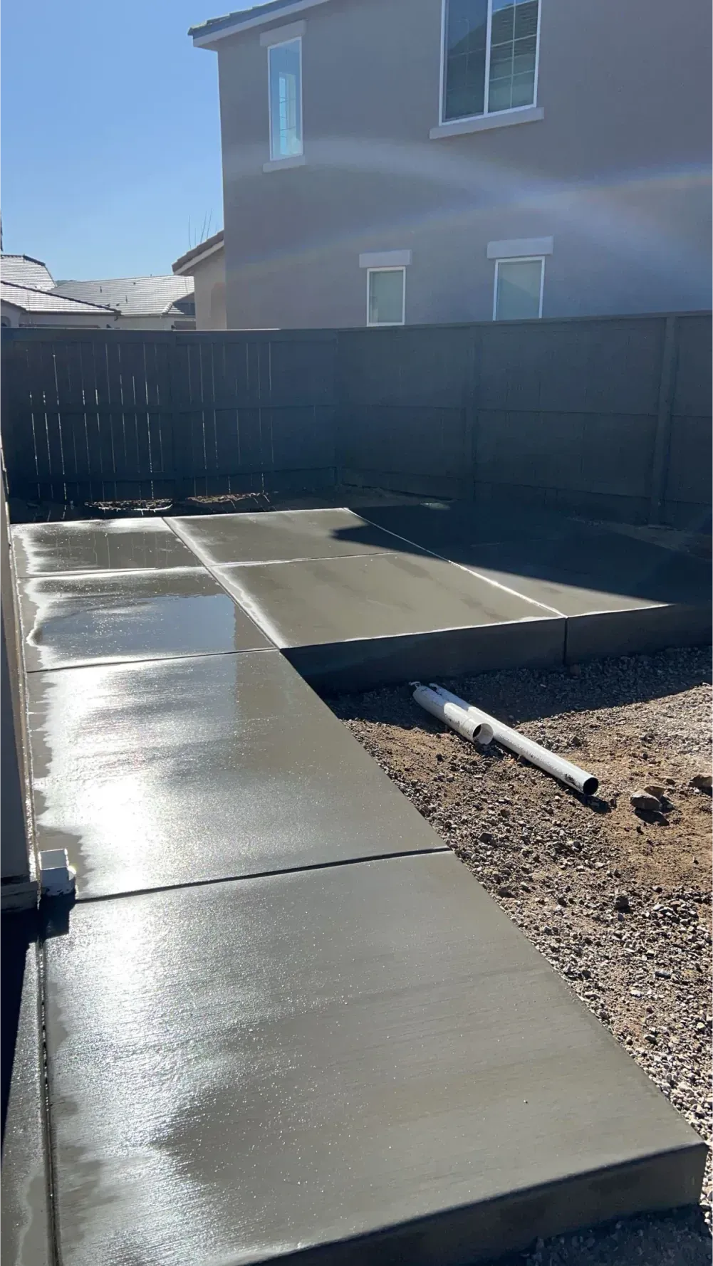 A concrete walkway is being built in the backyard of a house.