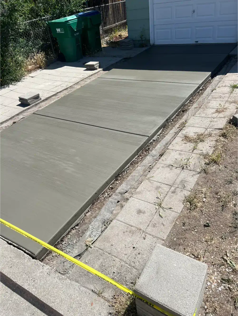 A concrete driveway is being built in front of a garage.