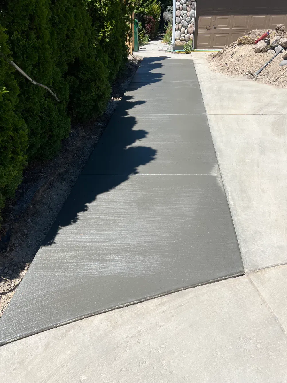 A concrete walkway leading to a house with trees in the background.