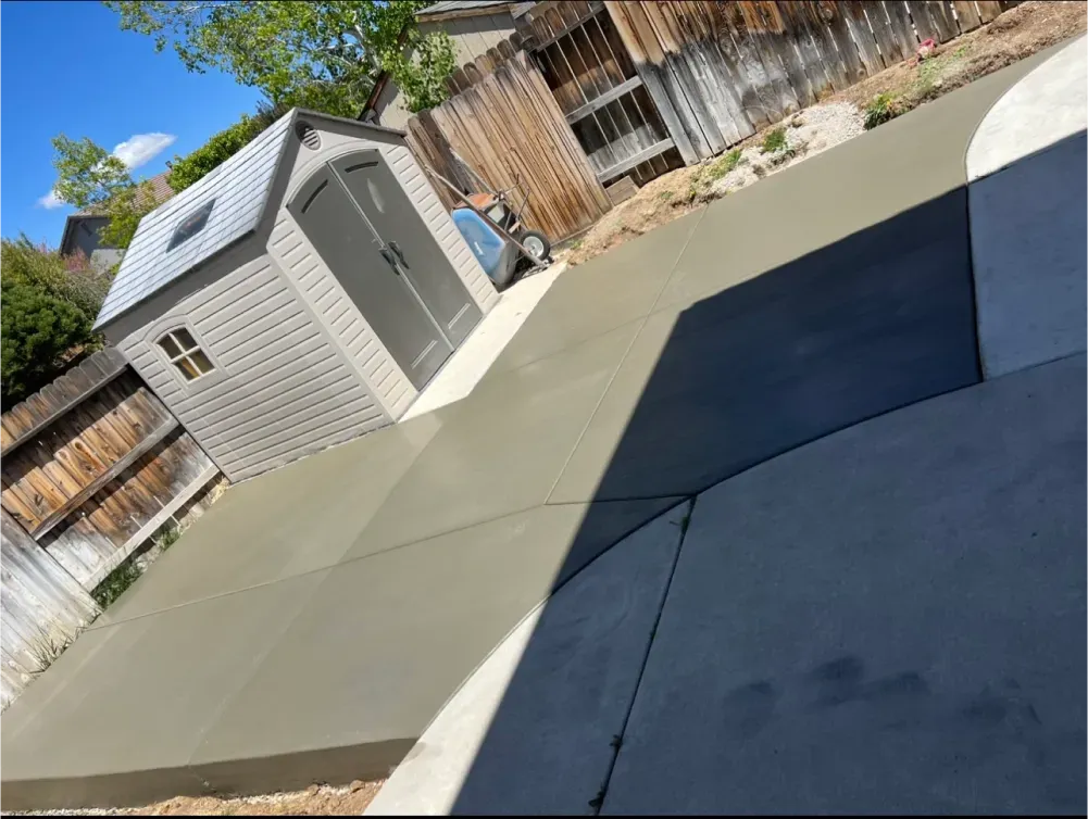 A shed is sitting on top of a concrete driveway.