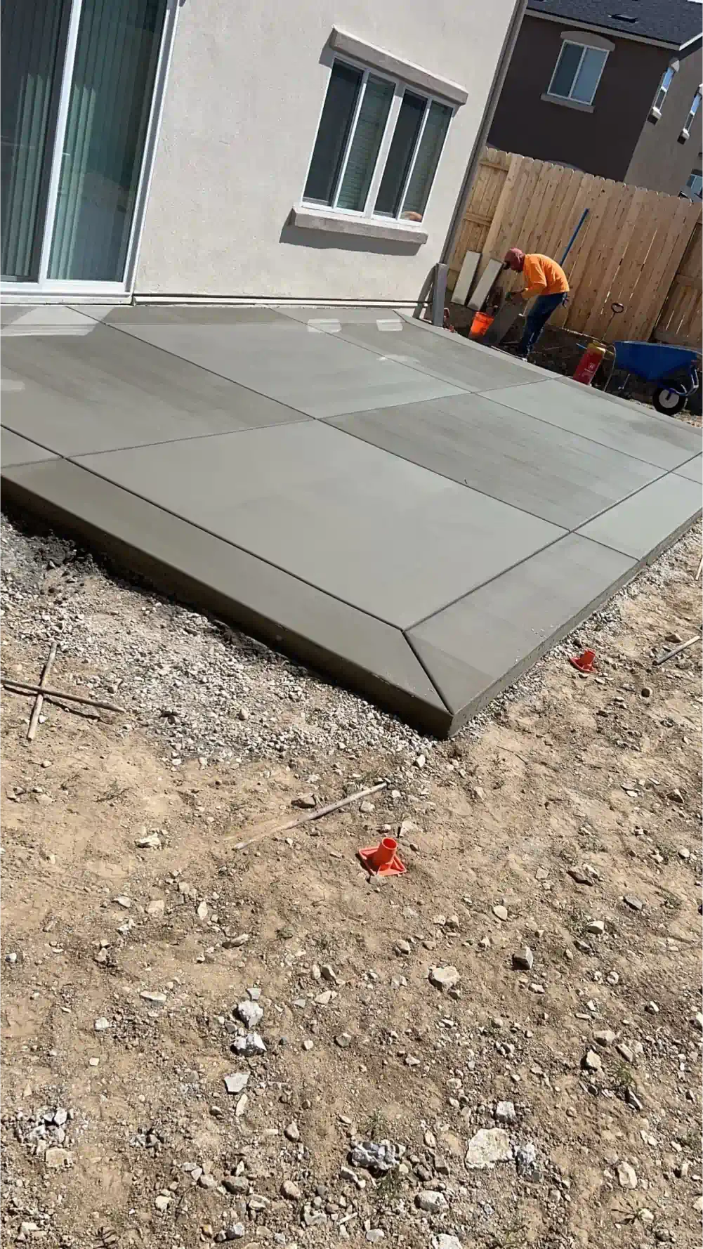 A man is working on a concrete patio in front of a house.