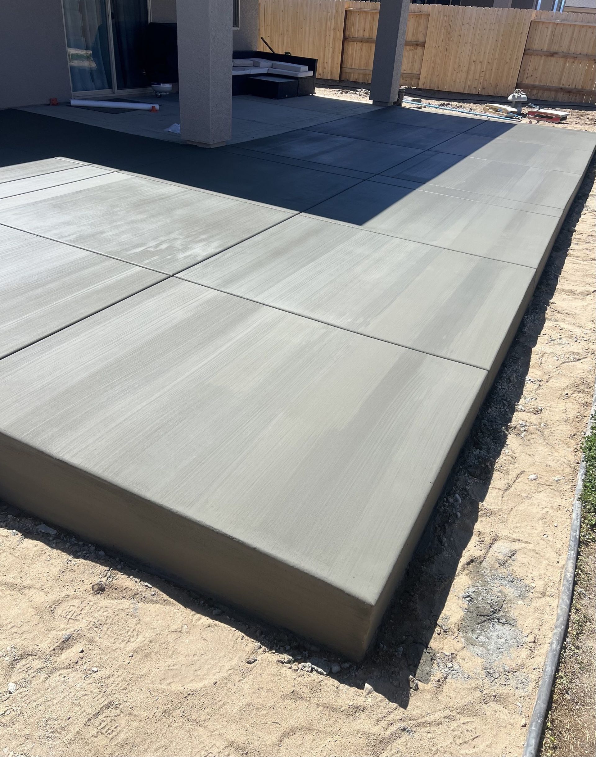 A concrete patio is being built in the backyard of a house.