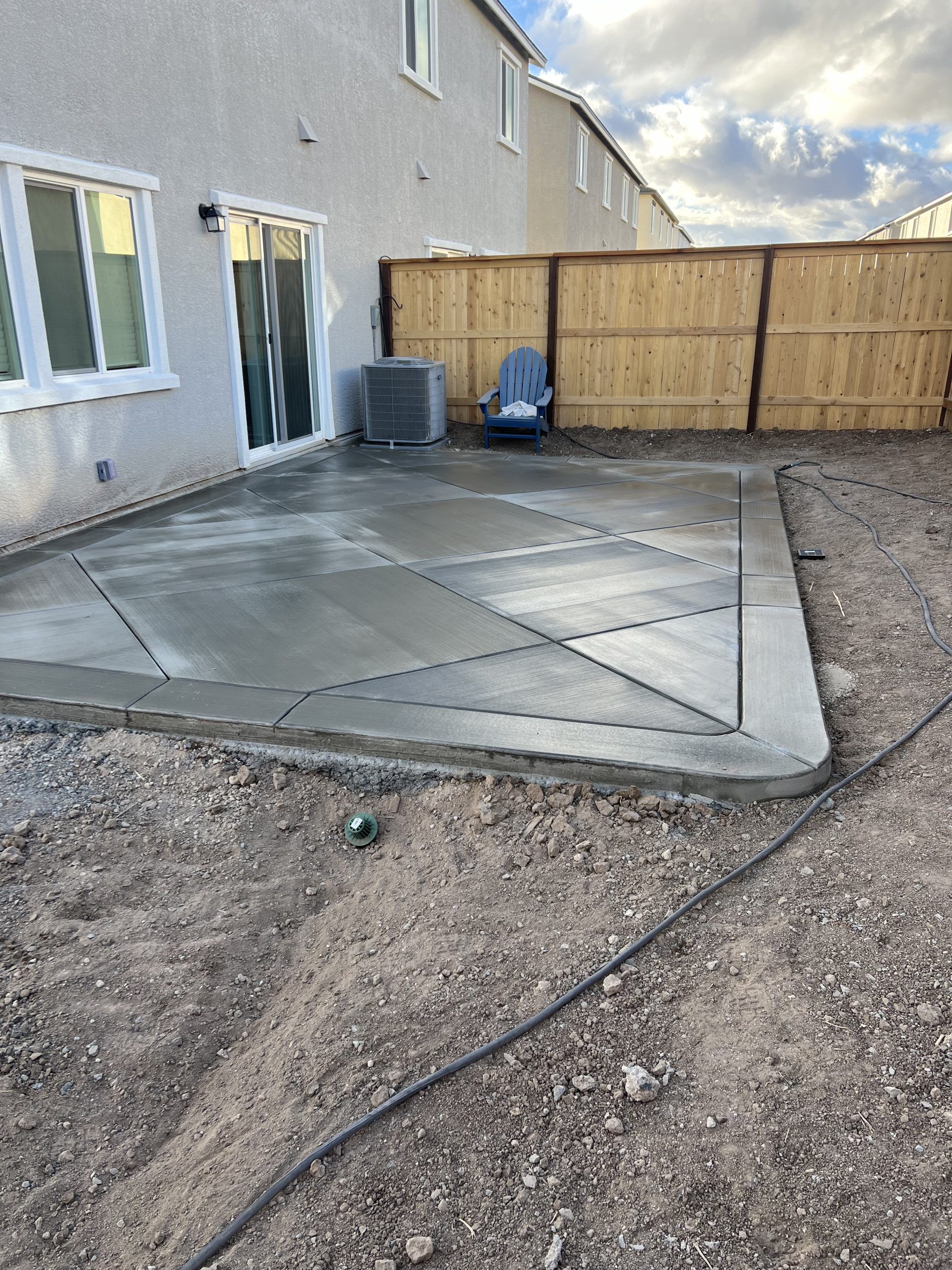 A concrete patio is being built in the backyard of a house.