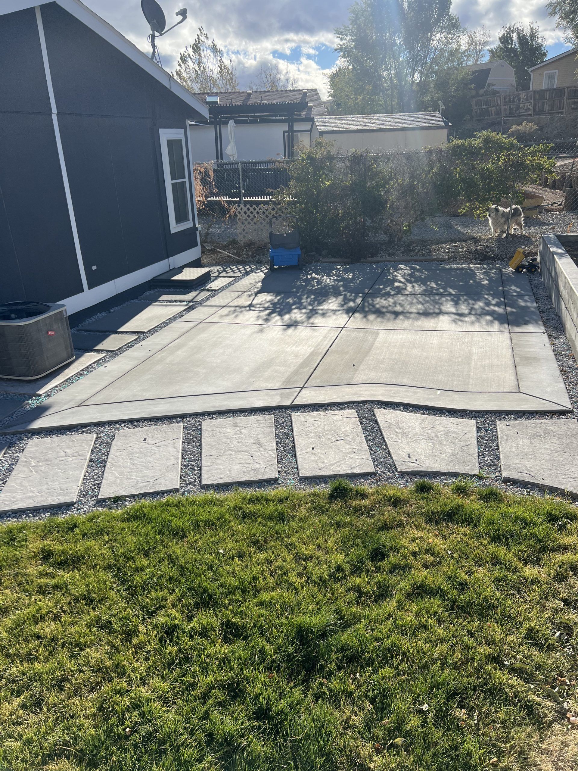 A backyard with a concrete patio and a shed in the background.