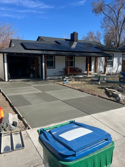 A car is parked in front of a house with a concrete driveway.
