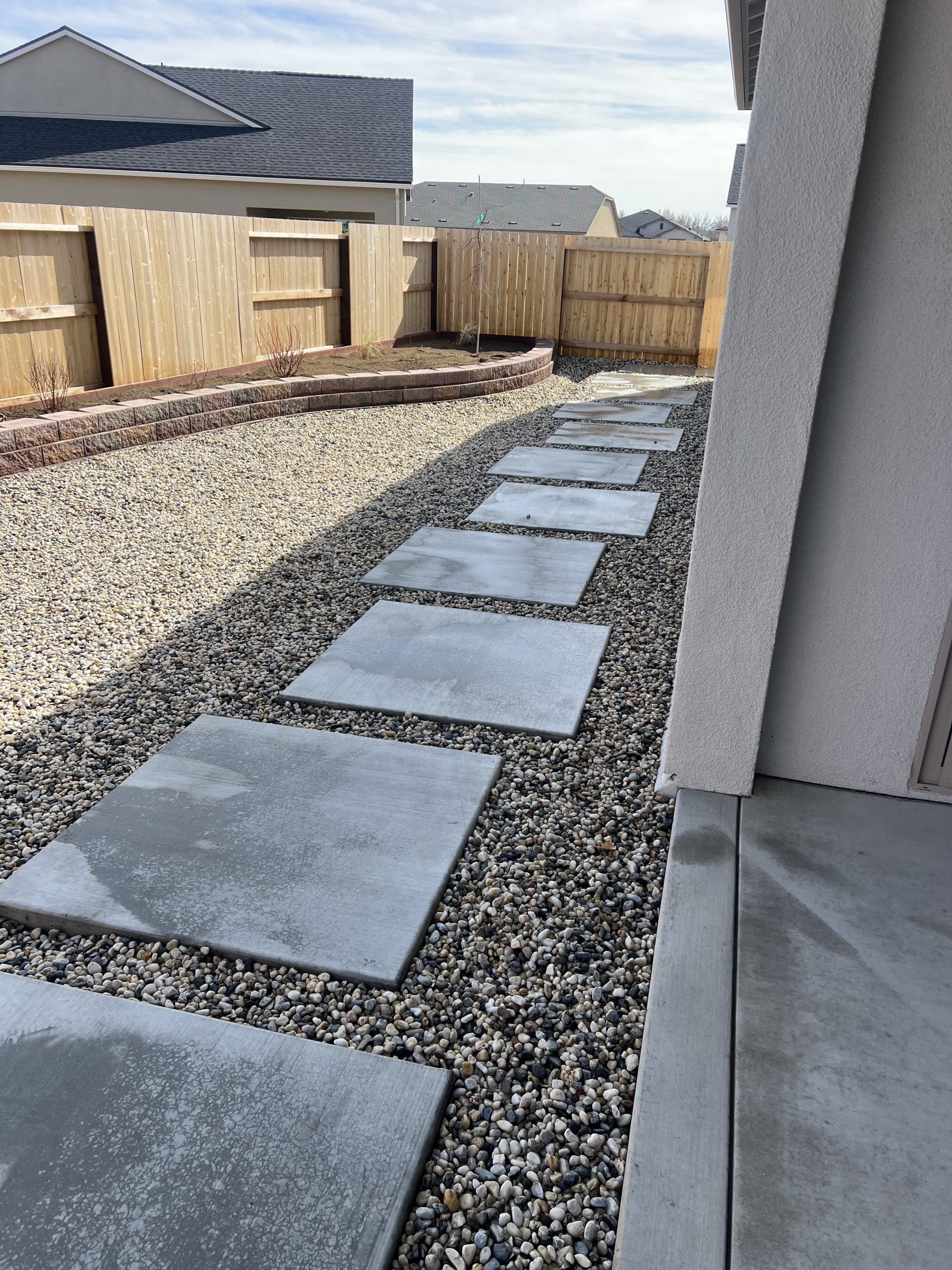 A walkway with concrete slabs and gravel in front of a house