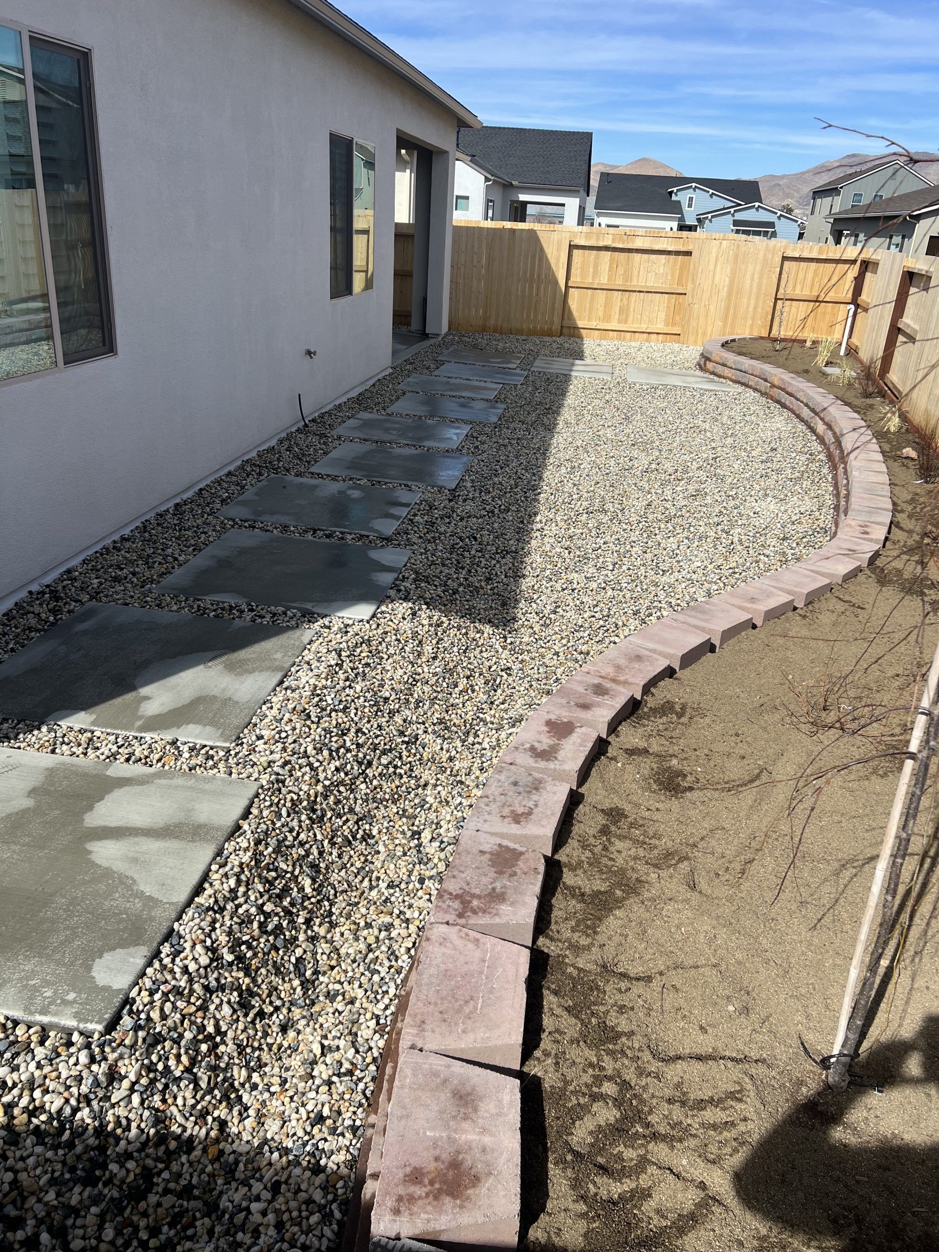 A house with a fence and gravel in front of it.