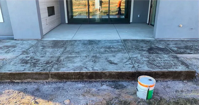 A bucket of paint is sitting on the ground in front of a building.