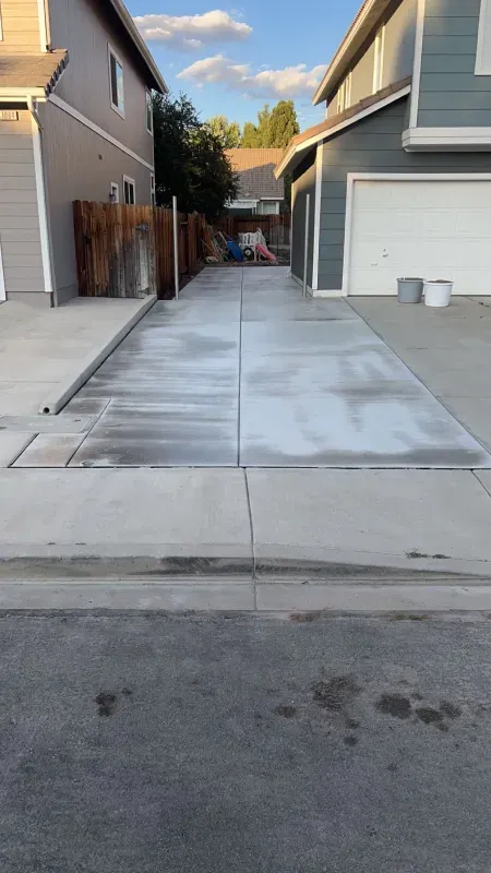 A concrete driveway between two houses in a residential neighborhood.