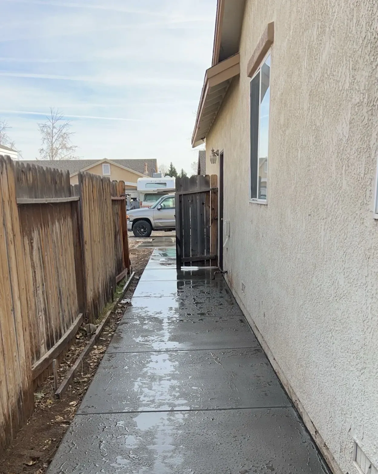 A sidewalk leading to a house with a fence in the background