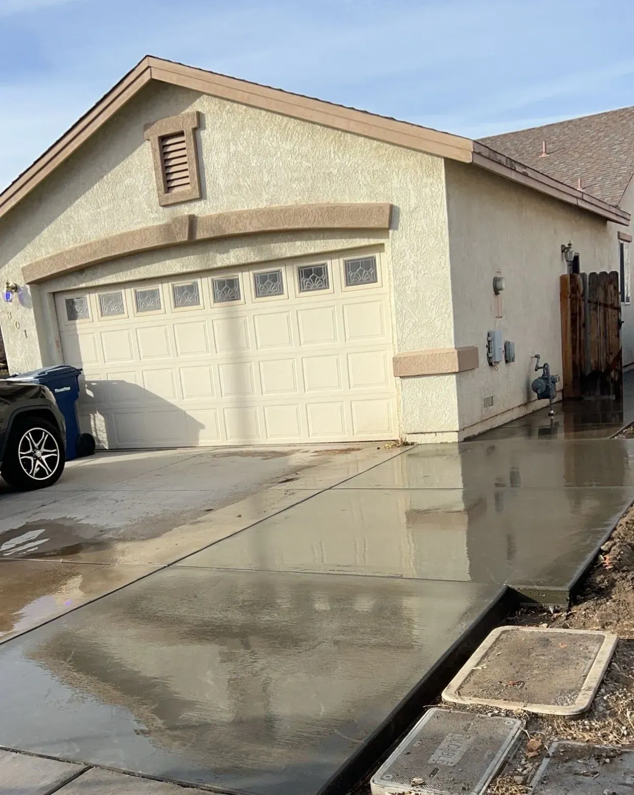 A car is parked in front of a house with a concrete driveway.