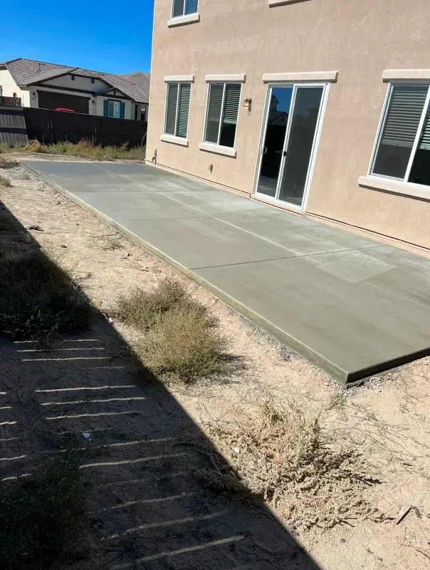 A concrete patio is being built in front of a house.