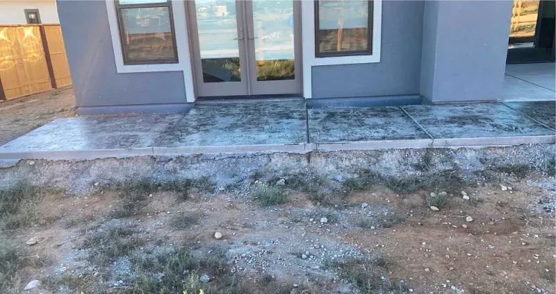 There is a concrete walkway in front of a house.