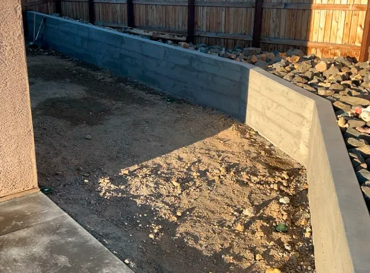 A concrete wall is being built next to a wooden fence.