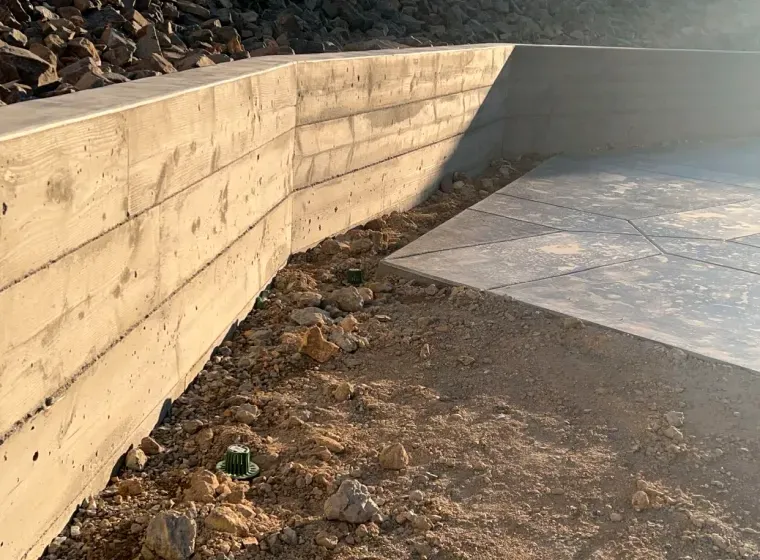 A concrete wall is being built next to a concrete driveway.