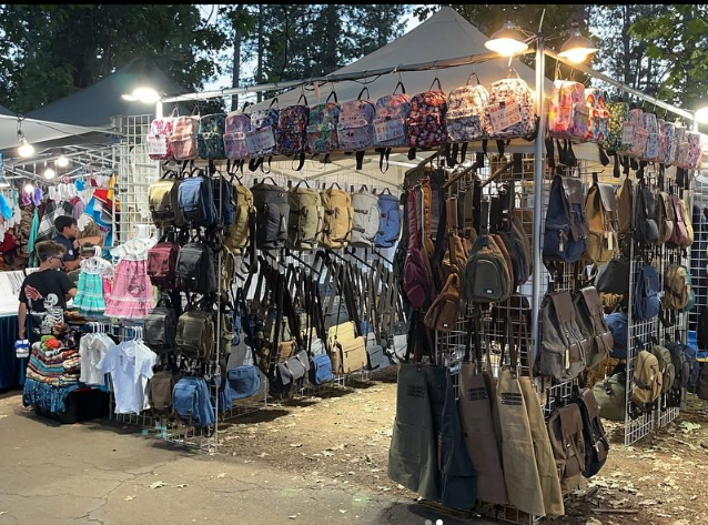 A bunch of backpacks are hanging on a rack at a market