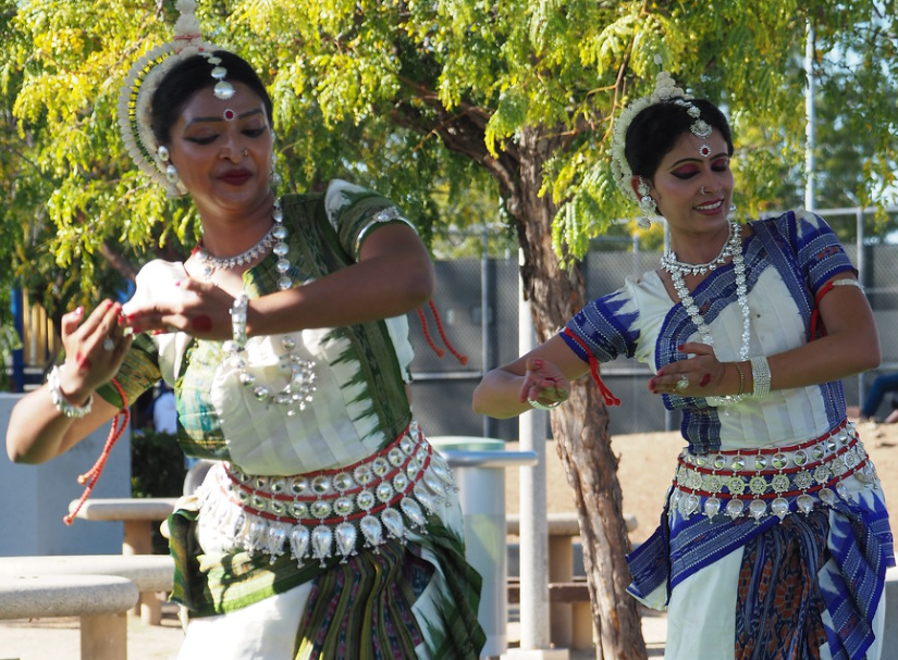 Two women in traditional indian costumes are dancing in a park