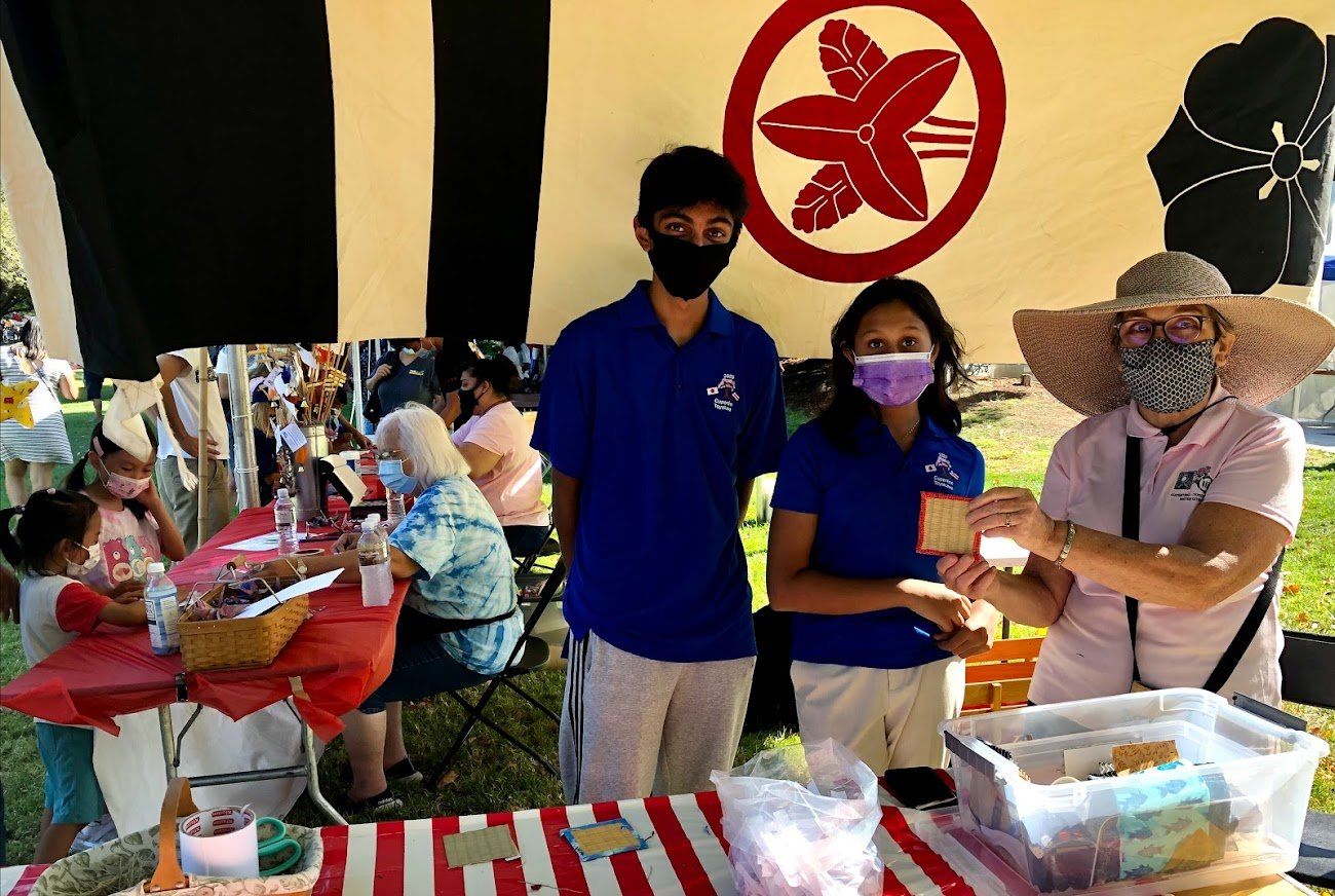 A group of people wearing masks are standing in front of a table.
