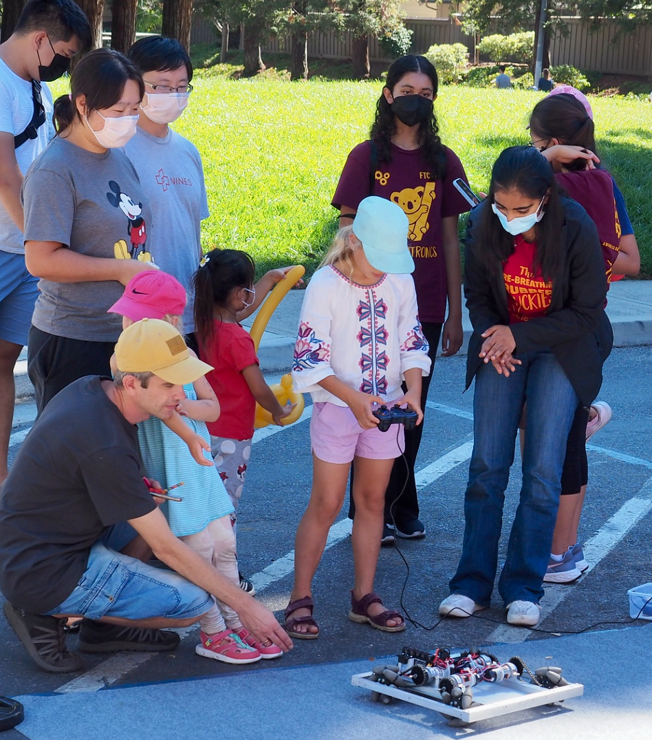A group of people wearing face masks are playing with a robot