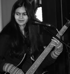 A woman is playing a guitar in front of a microphone.
