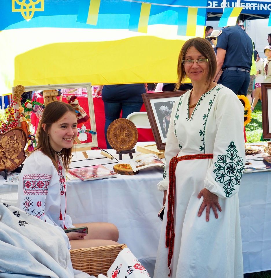 A woman in a white dress stands next to a woman sitting at a table