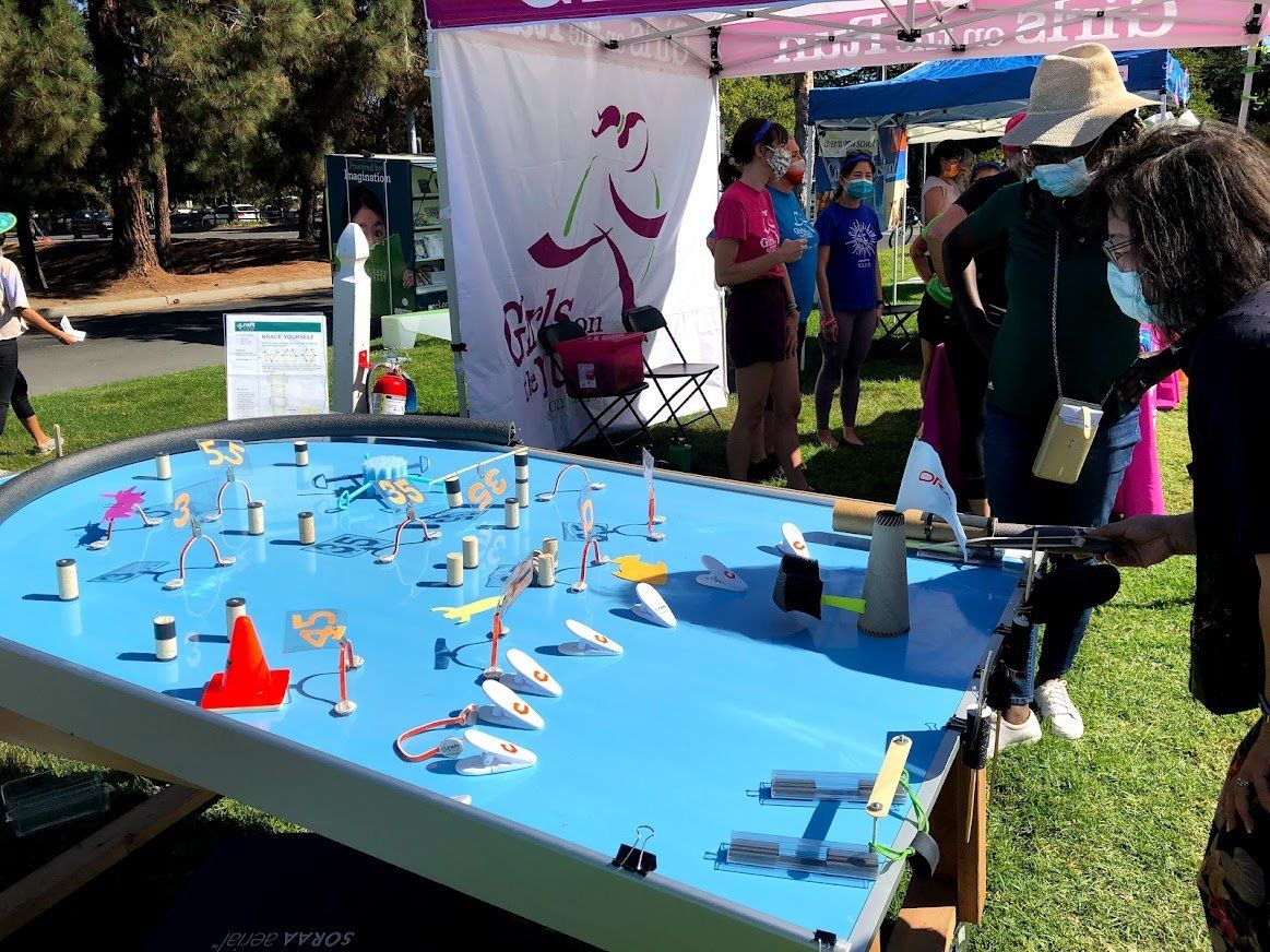 A group of people are standing around a table with a lot of toys on it.