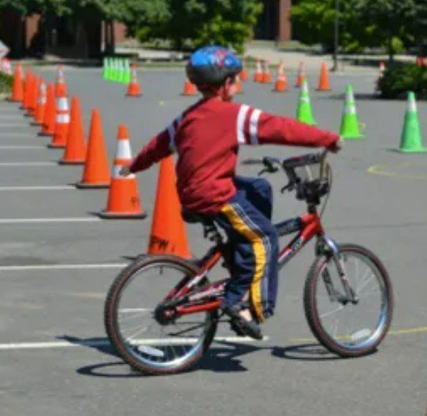A young boy wearing a helmet is riding a bike in a parking lot