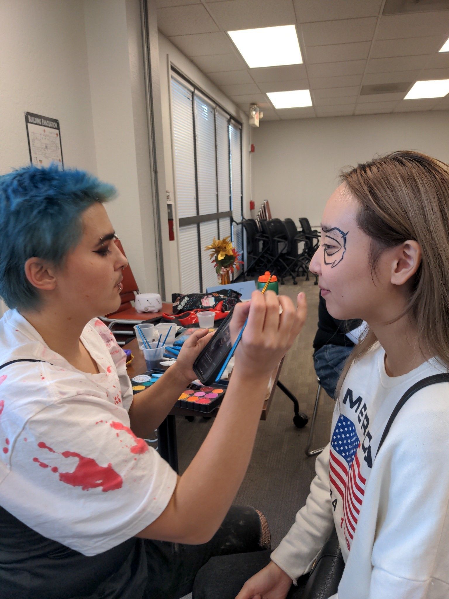 A woman in a witch hat is painting a child 's face