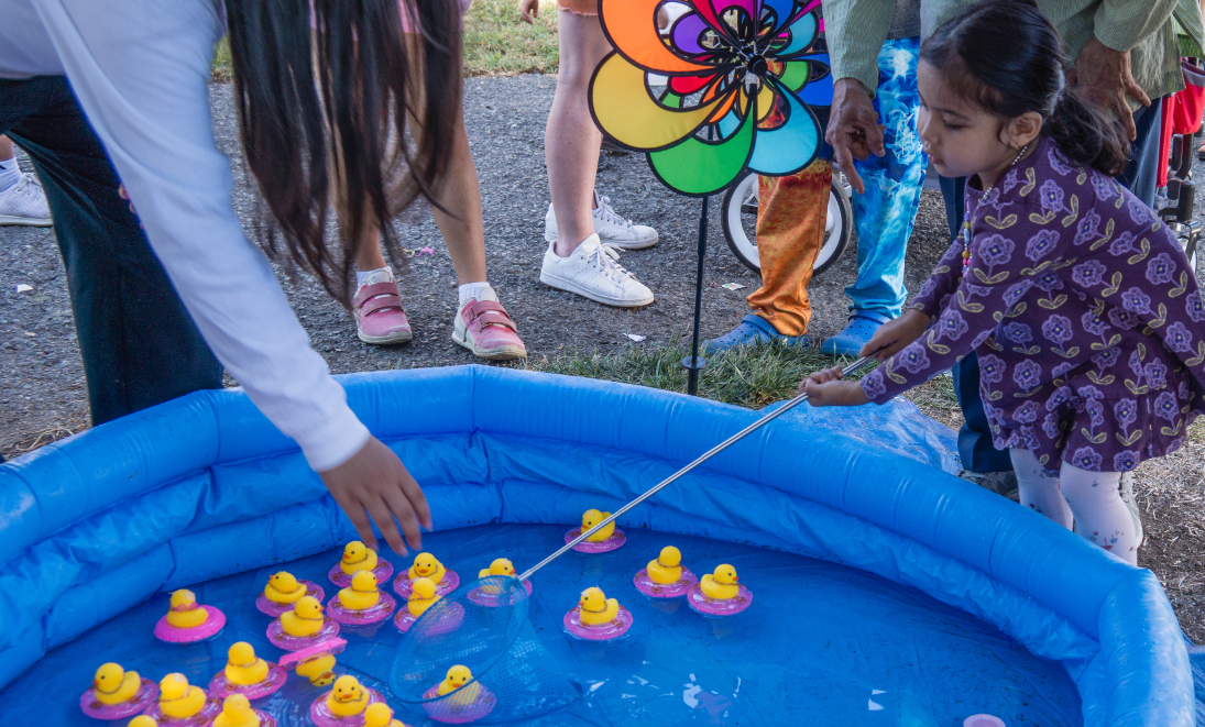 A group of children are playing bean bag toss in a park.