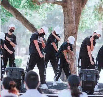 A group of people wearing masks are dancing on a stage in front of a crowd.