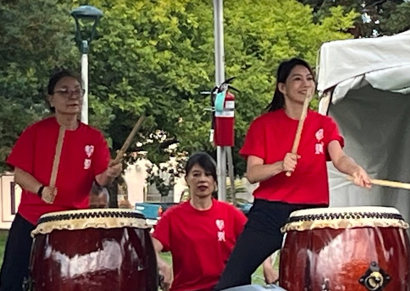 A group of people are playing drums in a park.