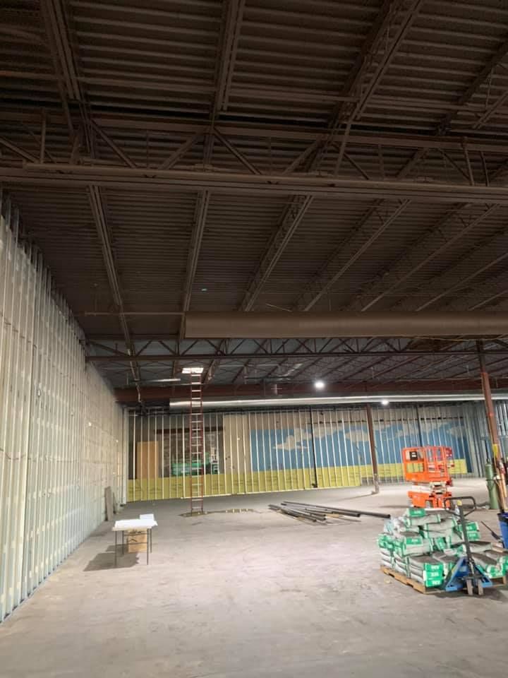 Interior of a large warehouse under construction. Walls are partially built; ceiling beams visible.
