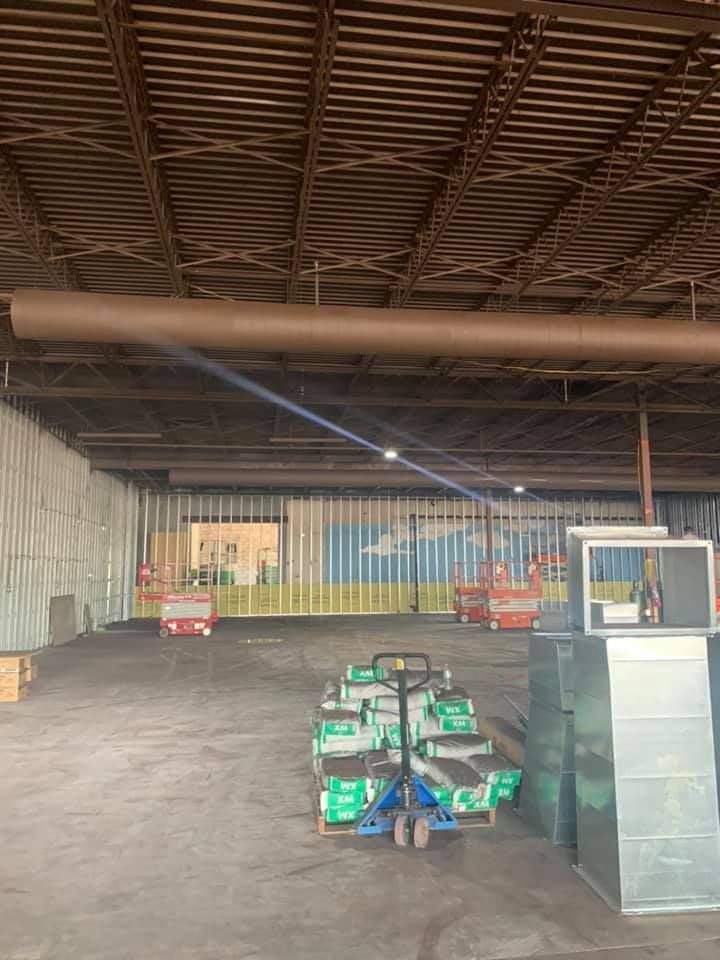 Warehouse interior with construction materials and equipment. Brown ductwork and ceiling.