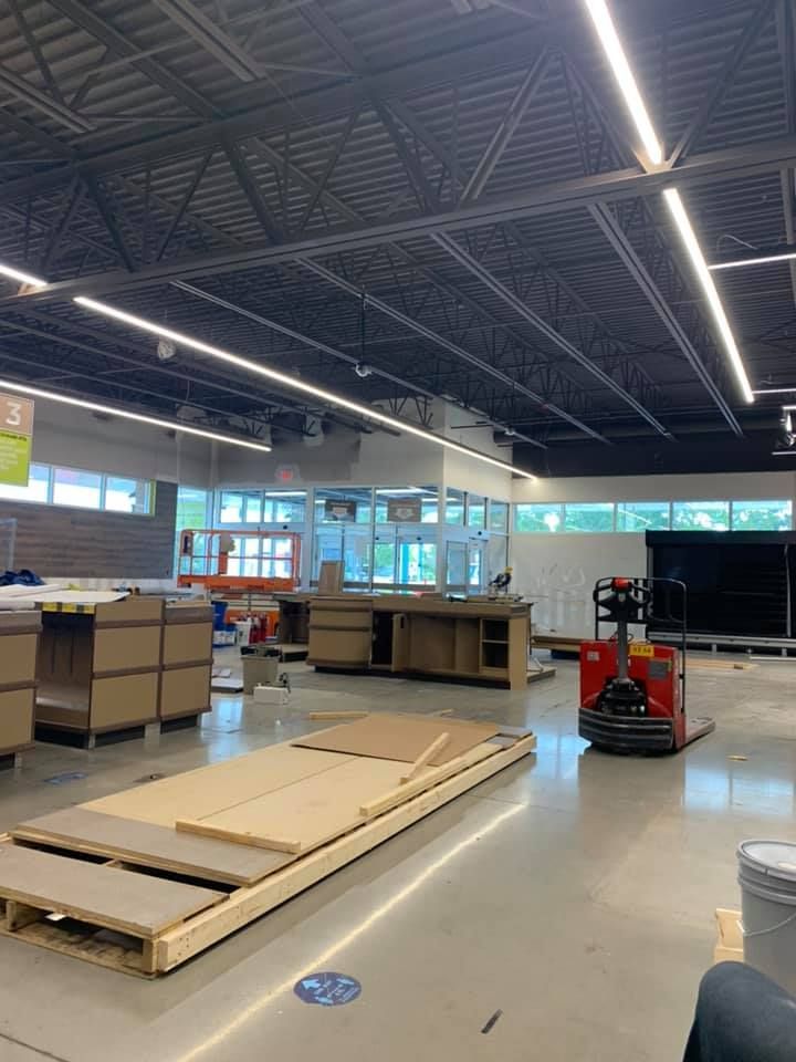 Interior of a store under construction; exposed ceiling, empty counters, pallets of materials and a pallet jack.