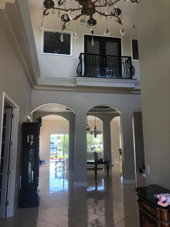 Grand foyer with chandelier, balcony, and arched doorways.