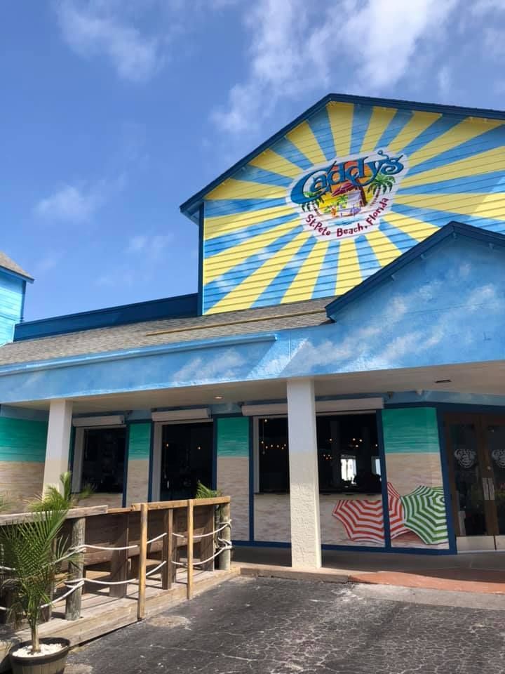 Brightly colored beachside restaurant: blue, yellow, and turquoise paint, with a blue sky background.